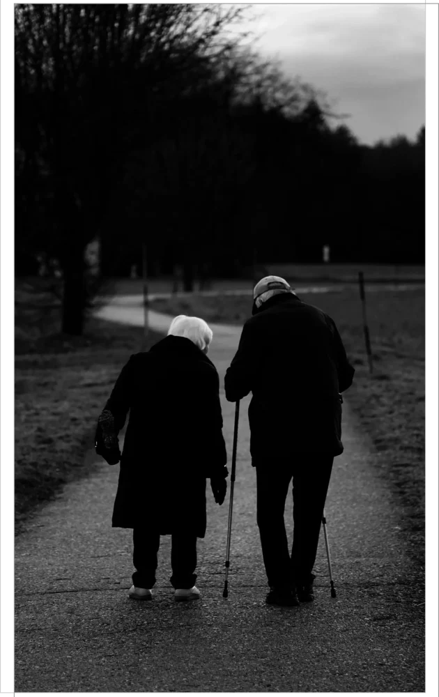 A black & White picture of an elderly couple walking in a park